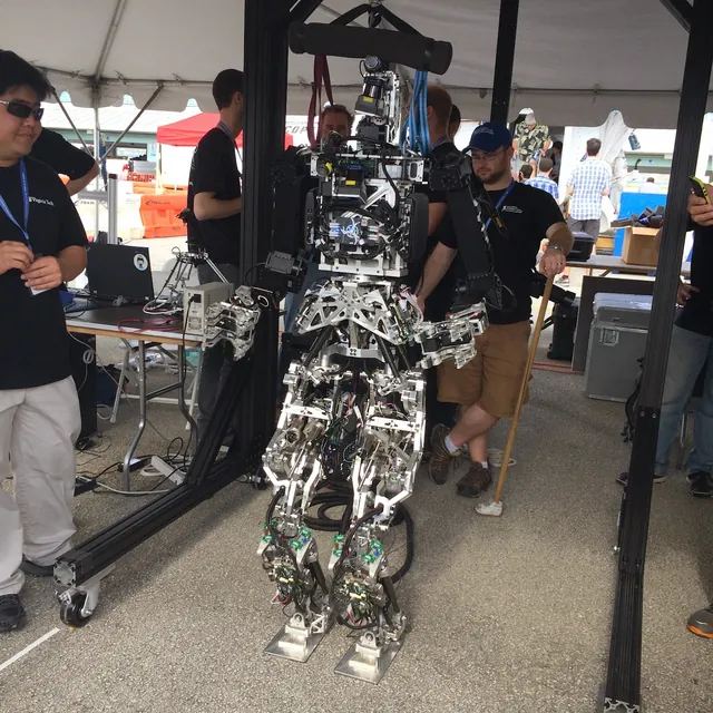 An exposed humanoid robot on a support rig at a robotics event. From the personal archive.