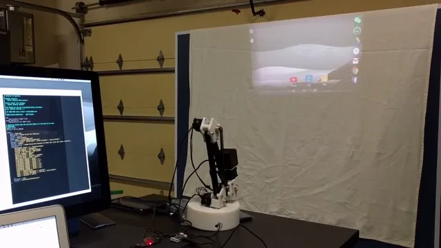 An articulated device mount moving in front of a projection screen in a workshop.